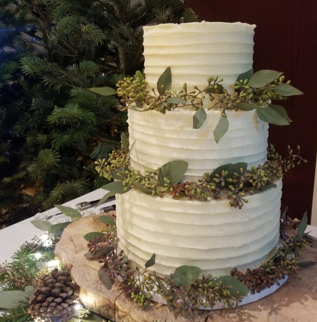 Wedding Cake decorated with Perfectly Perfect Vanilla Buttercream, surrounded with greenery.